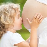 Barn kysser maven på gravid kvinde