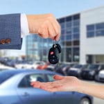 Bilnøgler skifter hænder foran en masse biler - køb af bil
