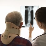 Mand med halskrave ser på røntgenfotos - piskesmæld
