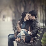 Par kysser på en bænk i parken - romantik