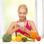 Ung kvinde tæller kalorier foran en masse sunde grøntsager