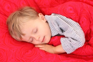 Lille dreng i stribet pyjamas sover